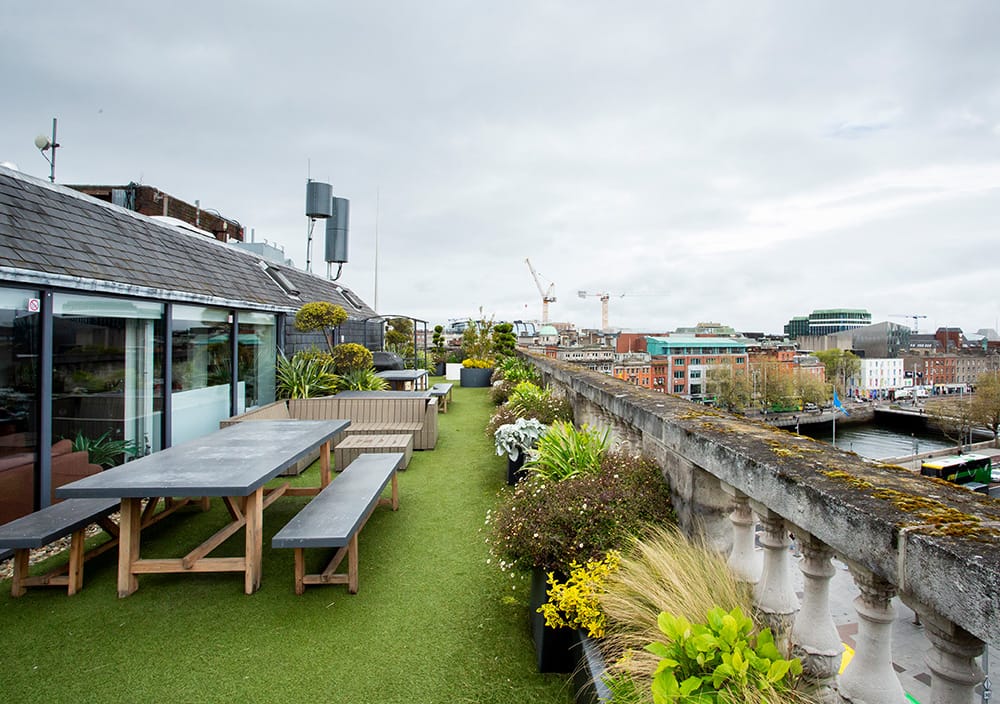 Rooftop office terrace with picnic tables, greenery, and views over Dublin's skyline